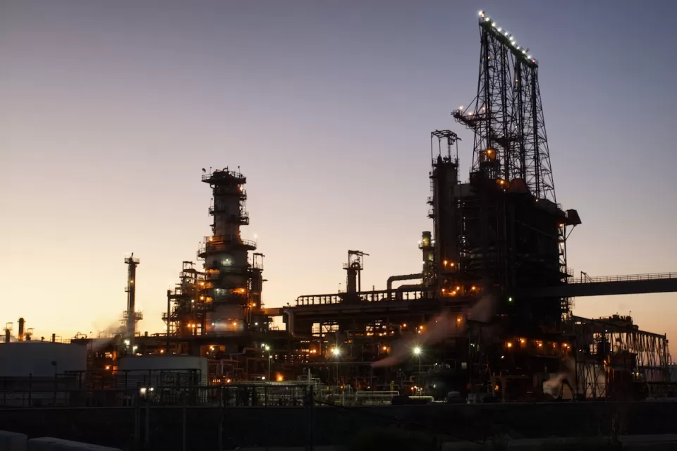 Oil refinery sillhouetted against evening sky.